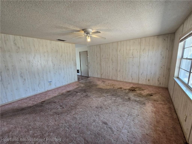 spare room featuring carpet floors, visible vents, a textured ceiling, and a ceiling fan