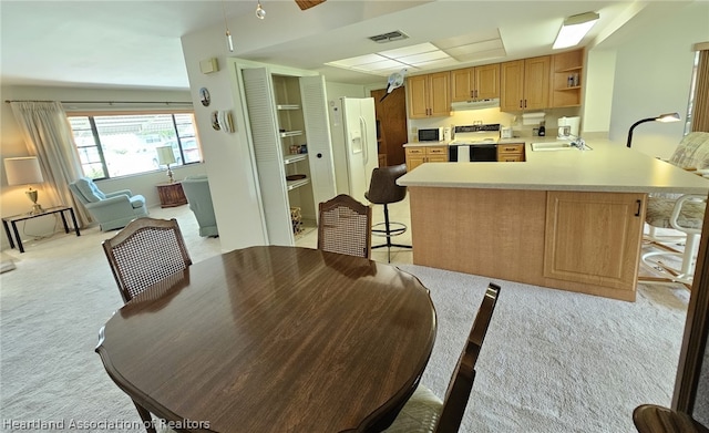 dining room featuring sink and light colored carpet