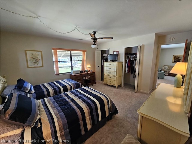 carpeted bedroom with ceiling fan, a walk in closet, and a closet