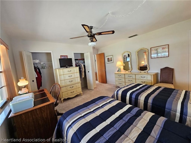 carpeted bedroom with ceiling fan and multiple closets