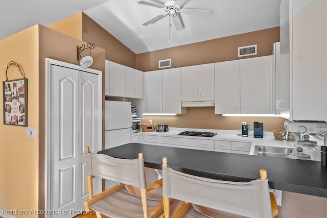 kitchen featuring a peninsula, a sink, visible vents, a ceiling fan, and freestanding refrigerator