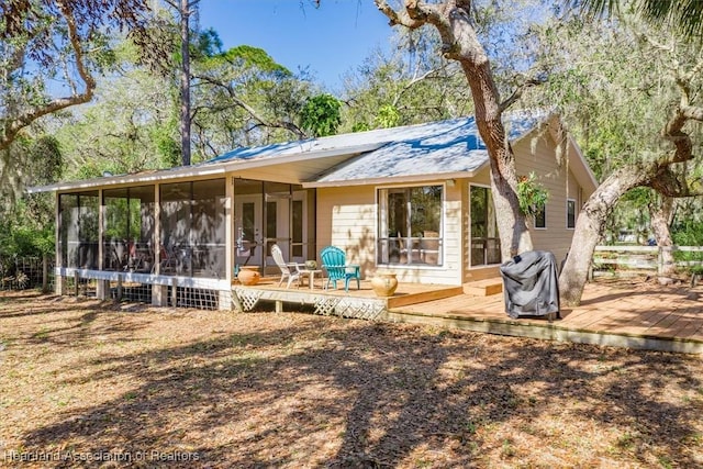 rear view of house featuring french doors, a wooden deck, and a sunroom