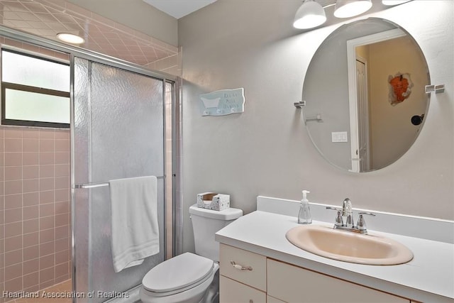 bathroom with toilet, a shower stall, and vanity