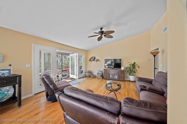 living area with a ceiling fan, visible vents, vaulted ceiling, and light wood finished floors