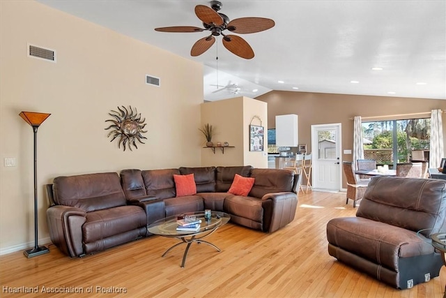 living area with vaulted ceiling, light wood-style flooring, visible vents, and baseboards