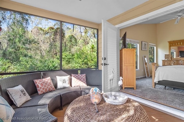 sunroom with lofted ceiling, a ceiling fan, and a wealth of natural light