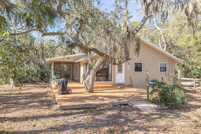 rear view of property featuring a sunroom and a deck