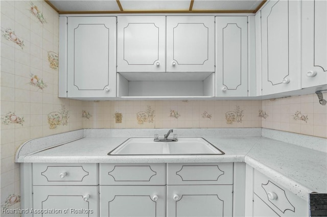 kitchen with decorative backsplash, white cabinetry, and sink