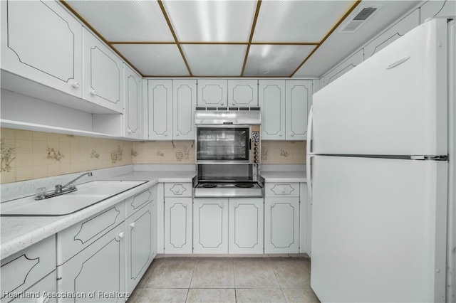 kitchen featuring sink, wall oven, stovetop, white fridge, and white cabinets