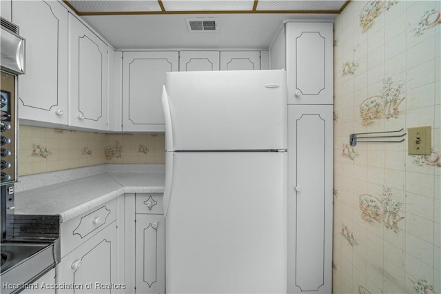 kitchen with white cabinets, decorative backsplash, and white refrigerator