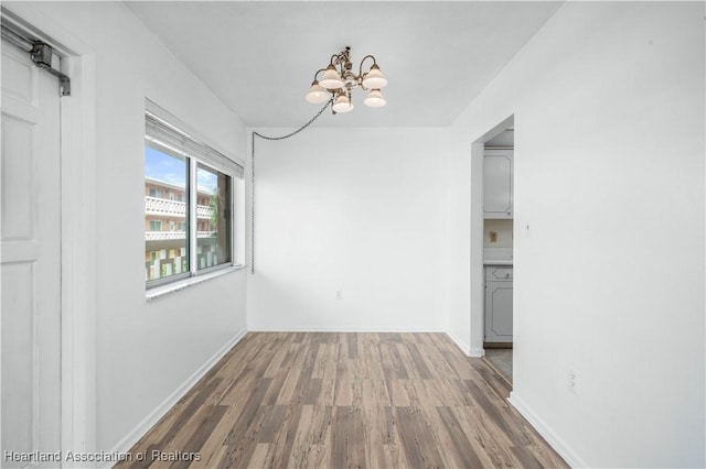 unfurnished dining area featuring dark wood-type flooring and a notable chandelier