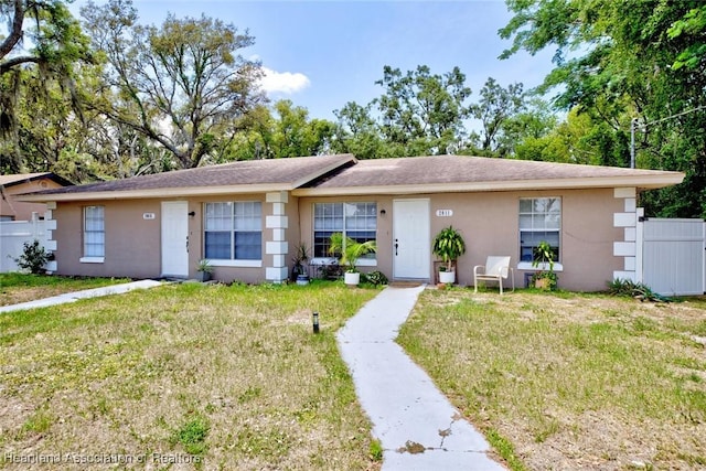ranch-style house with stucco siding, a front yard, and fence