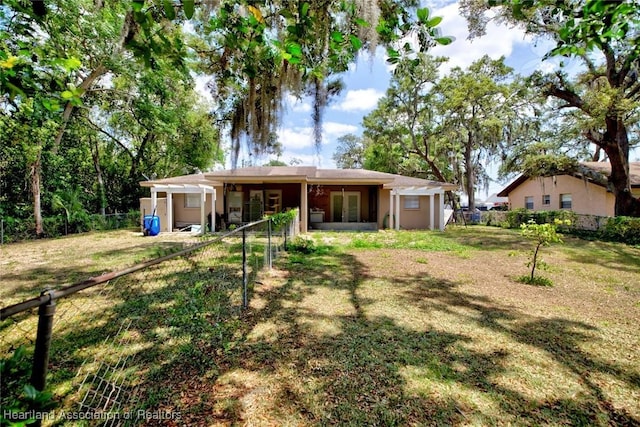 back of house featuring french doors, fence, and a lawn