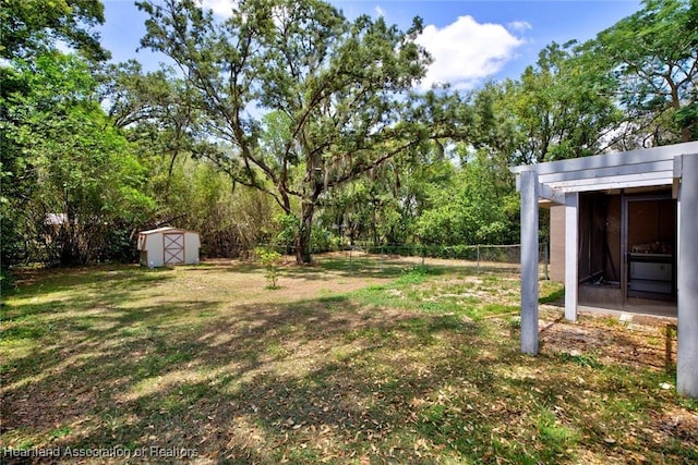 view of yard featuring an outdoor structure, fence, and a shed