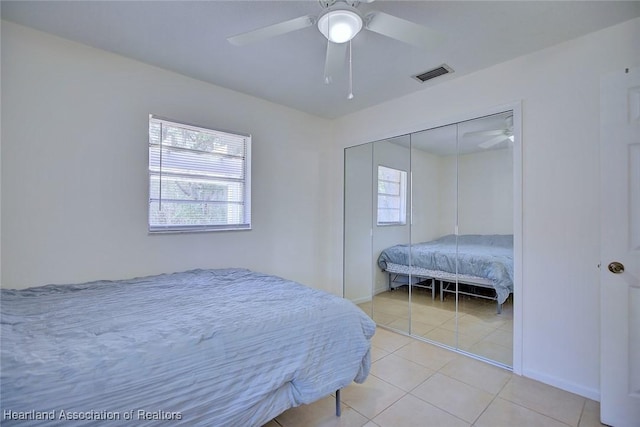 bedroom featuring light tile patterned flooring, a ceiling fan, baseboards, visible vents, and a closet