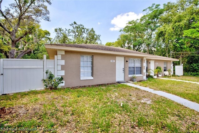 ranch-style house with fence, stucco siding, and a front lawn