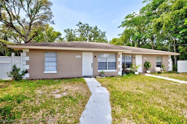 view of front of property with a front lawn, stucco siding, and fence