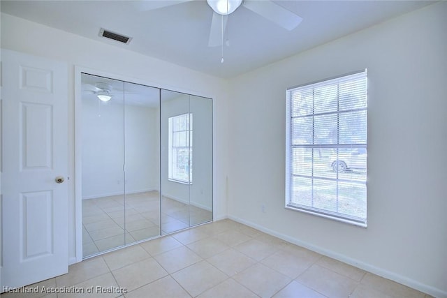 unfurnished bedroom featuring light tile patterned flooring, ceiling fan, baseboards, visible vents, and a closet