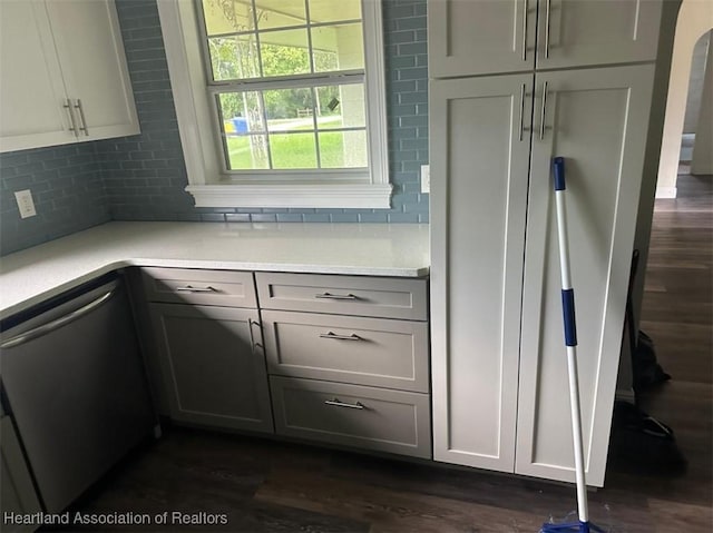 kitchen featuring backsplash, dishwasher, gray cabinets, and dark wood-type flooring