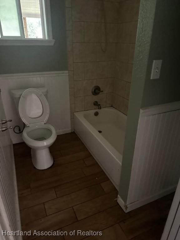 bathroom featuring hardwood / wood-style floors, toilet, and tiled shower / bath