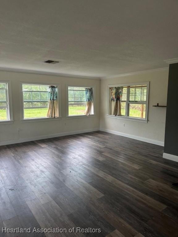 empty room featuring dark wood-type flooring and ornamental molding