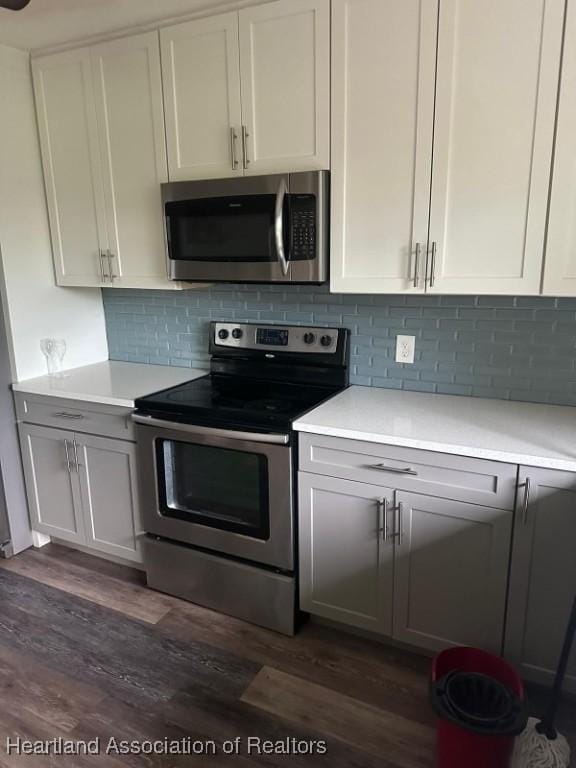 kitchen featuring white cabinets, appliances with stainless steel finishes, and dark hardwood / wood-style flooring