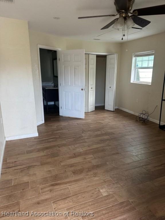 unfurnished bedroom featuring hardwood / wood-style floors, ceiling fan, and a closet