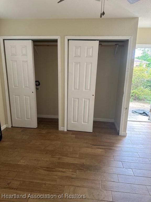 unfurnished bedroom with two closets and dark hardwood / wood-style floors