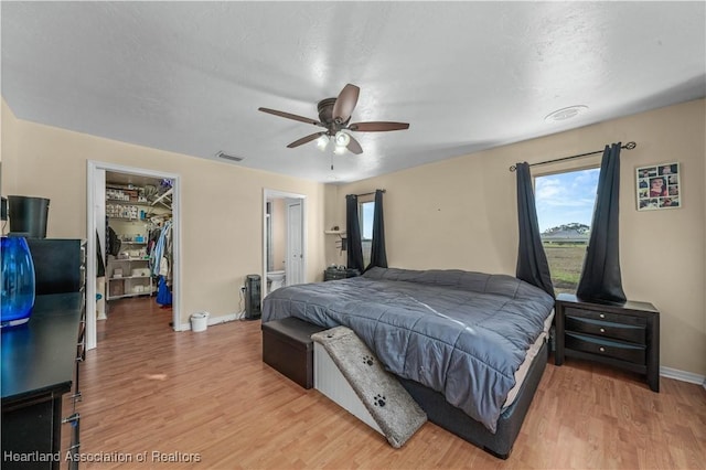 bedroom with ceiling fan, a closet, a walk in closet, and light hardwood / wood-style flooring