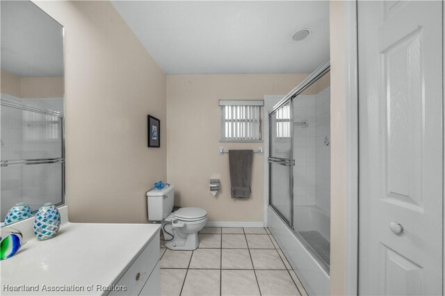 full bathroom with enclosed tub / shower combo, toilet, vanity, and tile patterned flooring