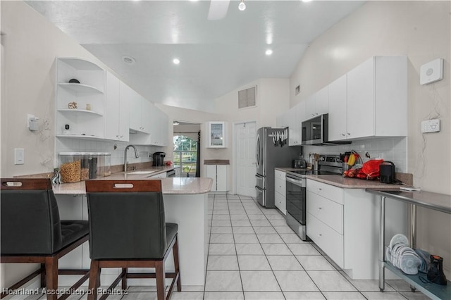 kitchen with white cabinets, vaulted ceiling, sink, and stainless steel appliances