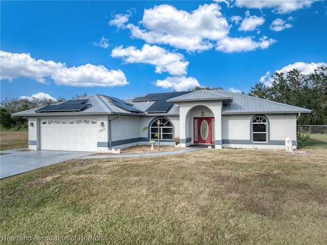 ranch-style home with a garage, a front lawn, and solar panels