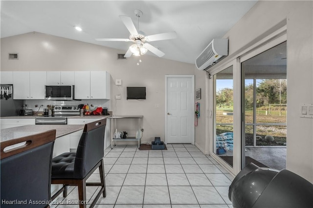 kitchen with lofted ceiling, white cabinets, an AC wall unit, and stainless steel appliances