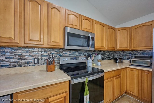 4703 Benton St, Lake Wales, FL 33859 - kitchen featuring stainless steel appliances, vaulted ceiling, tasteful backsplash, light countertops, and light tile patterned floors
