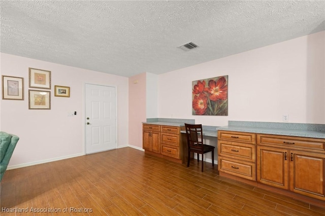 5808 Twisted Oaks Dr, Sebring, FL 33876 - office space with dark wood-style floors, built in desk, a textured ceiling, and baseboards