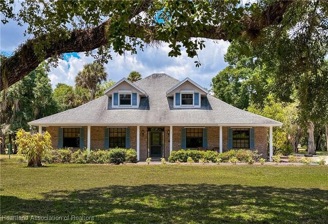 view of front of property with brick siding, covered porch, and a front lawn