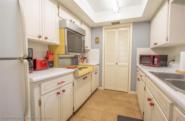 kitchen with light tile patterned floors, sink, and white fridge