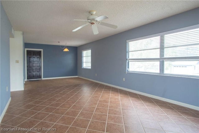 tiled empty room featuring ceiling fan and a textured ceiling