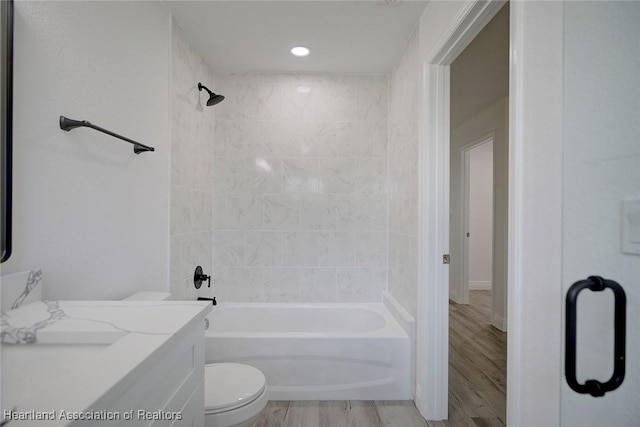 full bathroom with vanity, hardwood / wood-style flooring, toilet, and tiled shower / bath combo