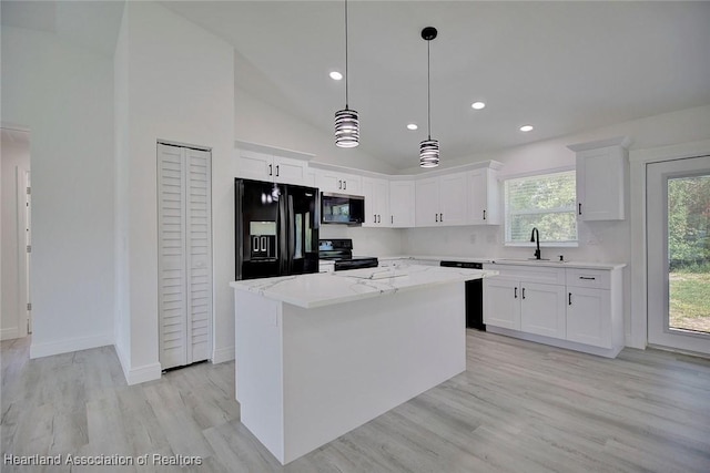 kitchen with a center island, black appliances, white cabinets, sink, and vaulted ceiling