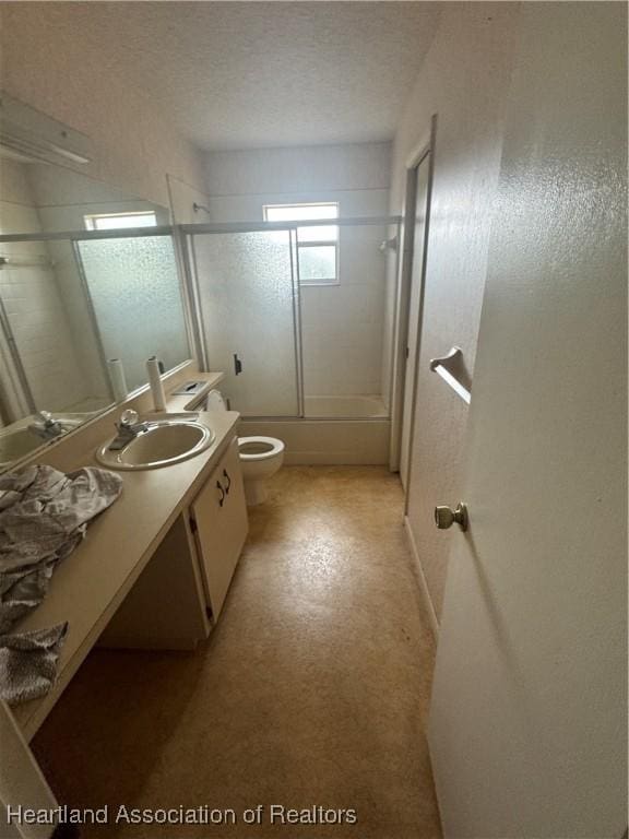 full bathroom featuring vanity, toilet, combined bath / shower with glass door, and a textured ceiling