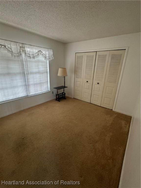 unfurnished bedroom with carpet flooring, a textured ceiling, and a closet