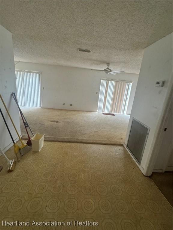 spare room with ceiling fan, light colored carpet, and a textured ceiling