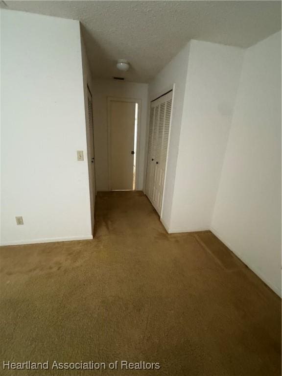 hall with a textured ceiling and carpet flooring