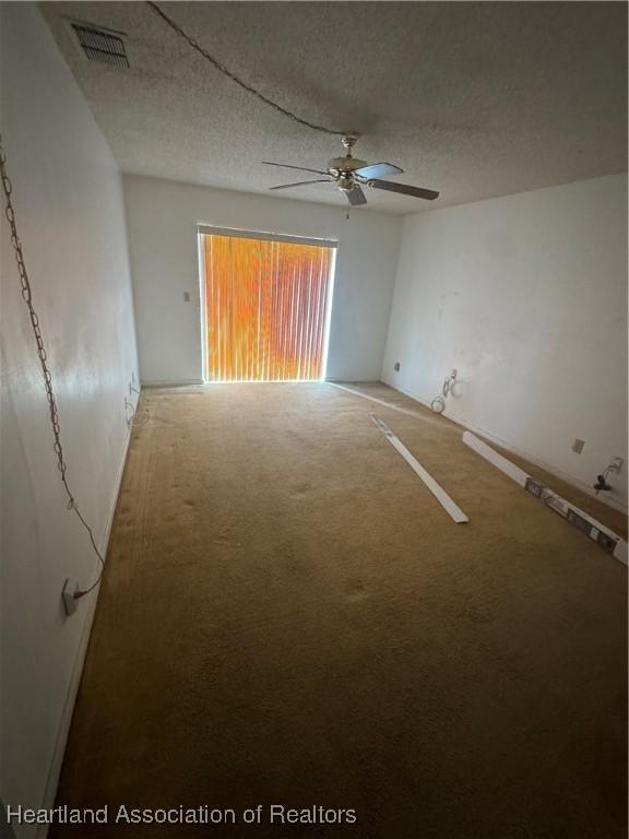 spare room featuring ceiling fan, a textured ceiling, and carpet