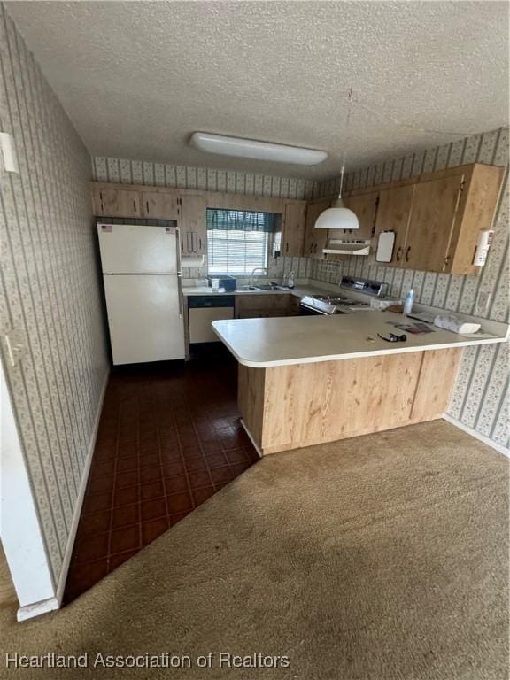 kitchen with pendant lighting, range, kitchen peninsula, and white fridge