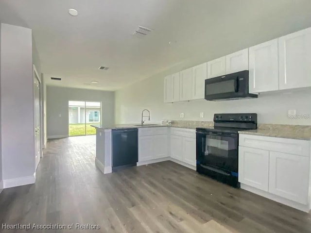 kitchen with dark wood-type flooring, black appliances, white cabinets, sink, and kitchen peninsula