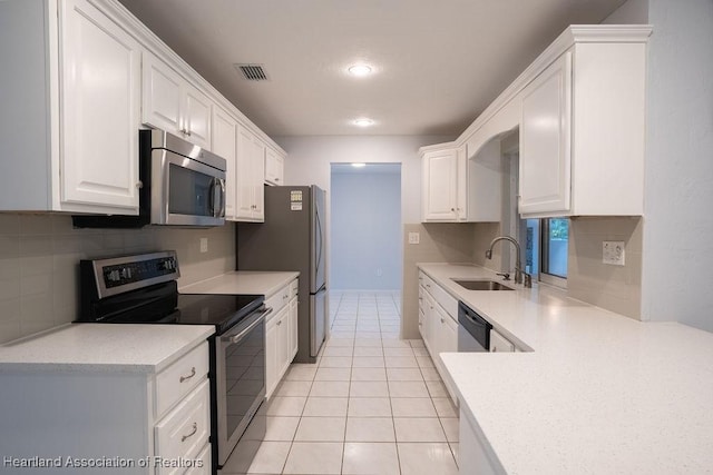 kitchen with sink, light tile patterned flooring, stainless steel appliances, and white cabinetry