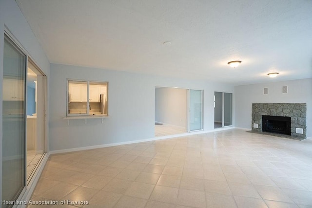 unfurnished living room featuring a stone fireplace