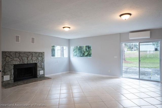 unfurnished living room with a textured ceiling, light tile patterned flooring, a stone fireplace, and a wall mounted air conditioner